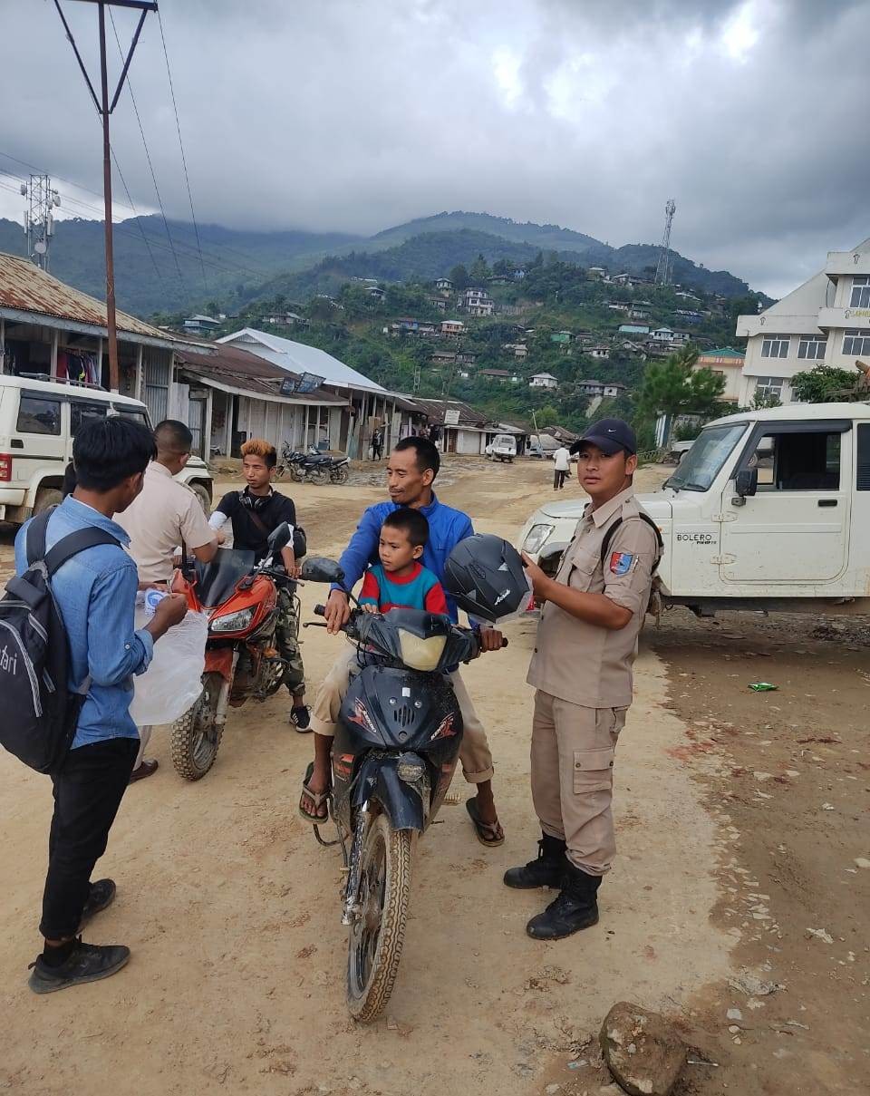 Student Police Cadet, Noklak distributing helmets and pasting safety stickers on vehicles. 